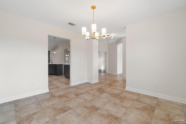 spare room with sink and an inviting chandelier