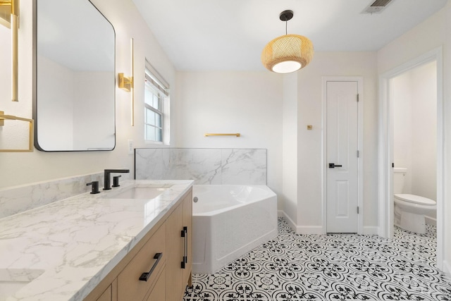 bathroom with a washtub, vanity, and toilet