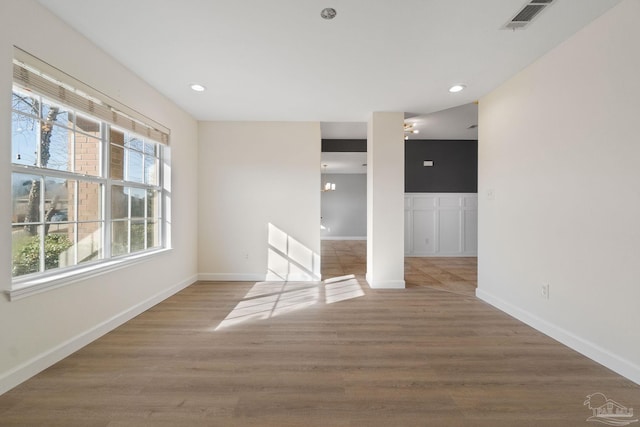 spare room featuring wood-type flooring and a notable chandelier