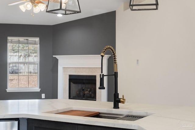 room details featuring a fireplace, ceiling fan, sink, and light stone counters