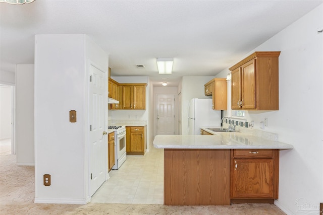 939 Avalon Blvd, Milton, FL 32583 - kitchen featuring white appliances, light countertops, a peninsula, under cabinet range hood, and brown cabinetry