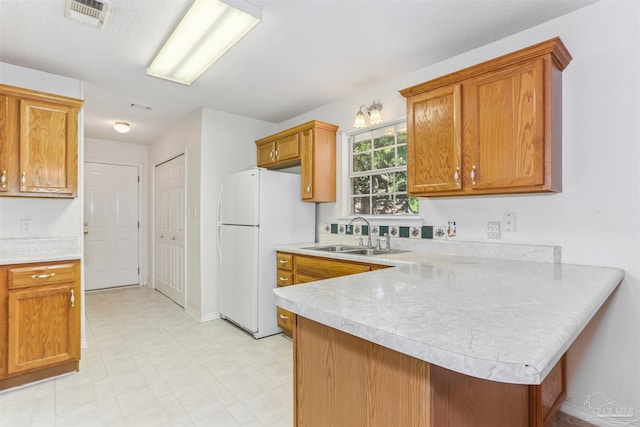 939 Avalon Blvd, Milton, FL 32583 - kitchen featuring freestanding refrigerator, light countertops, a peninsula, and brown cabinetry