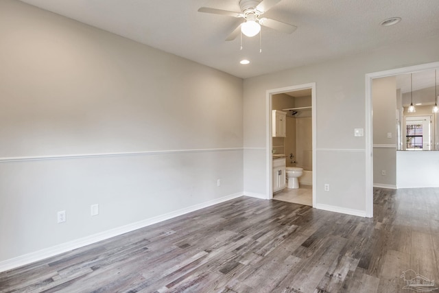 unfurnished bedroom featuring baseboards, ensuite bath, ceiling fan, wood finished floors, and recessed lighting