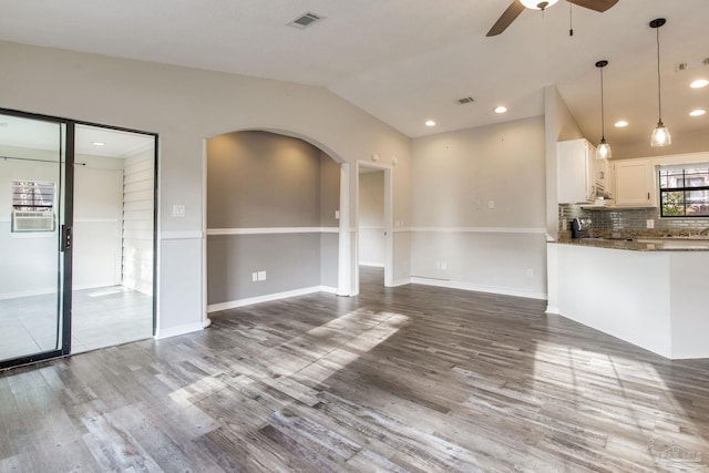 unfurnished living room featuring arched walkways, wood finished floors, visible vents, and a ceiling fan