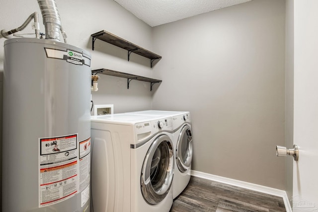 clothes washing area with laundry area, baseboards, washer and clothes dryer, wood finished floors, and gas water heater