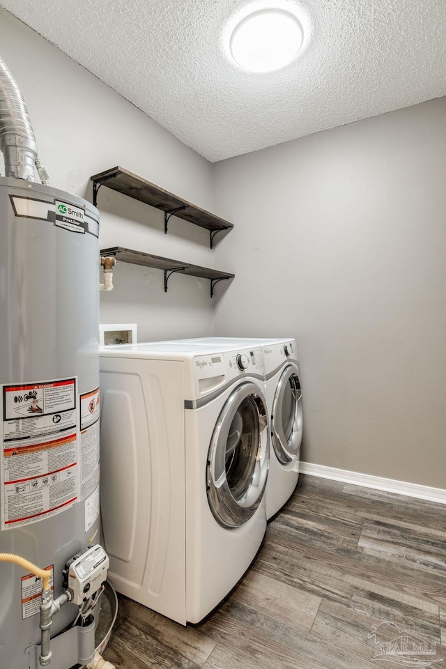 laundry area featuring gas water heater, washing machine and dryer, a textured ceiling, wood finished floors, and laundry area