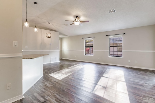 spare room with dark wood finished floors, visible vents, ceiling fan, and a textured ceiling