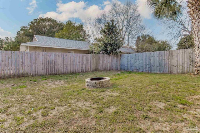 view of yard featuring a fenced backyard and a fire pit