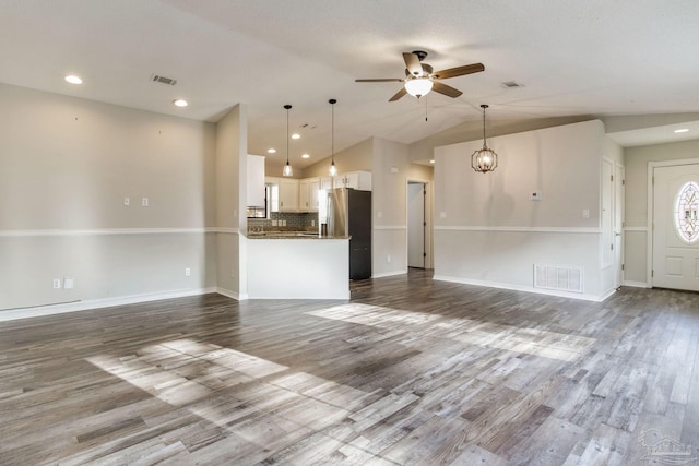 unfurnished living room with dark wood-style floors, visible vents, vaulted ceiling, and ceiling fan with notable chandelier