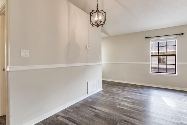 empty room featuring a chandelier, a textured ceiling, dark wood-style flooring, visible vents, and baseboards