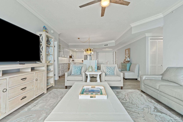 living room featuring a textured ceiling, wood-type flooring, and crown molding