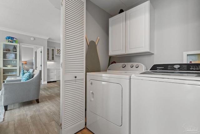 clothes washing area featuring washing machine and dryer, crown molding, cabinets, and light hardwood / wood-style floors