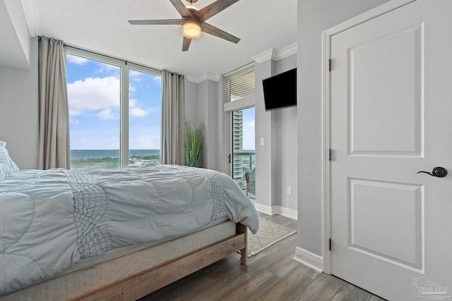 bedroom featuring hardwood / wood-style floors, ceiling fan, a water view, and ornamental molding