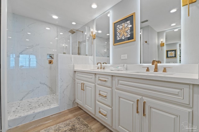 bathroom with a tile shower, vanity, and wood-type flooring