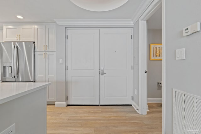 kitchen featuring white cabinetry, stainless steel fridge with ice dispenser, ornamental molding, and light hardwood / wood-style flooring