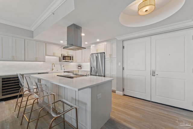 kitchen featuring white cabinets, a kitchen breakfast bar, light hardwood / wood-style floors, appliances with stainless steel finishes, and island range hood