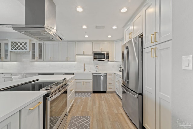 kitchen featuring light wood-type flooring, wall chimney exhaust hood, stainless steel appliances, sink, and white cabinetry