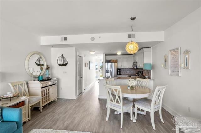 dining area with baseboards, visible vents, and wood finished floors