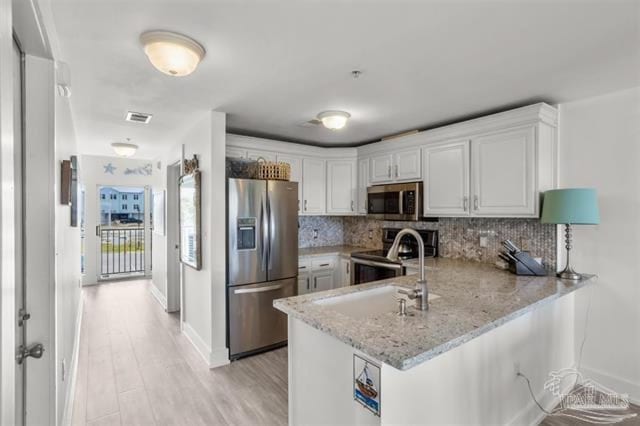 kitchen featuring a peninsula, appliances with stainless steel finishes, visible vents, and white cabinets