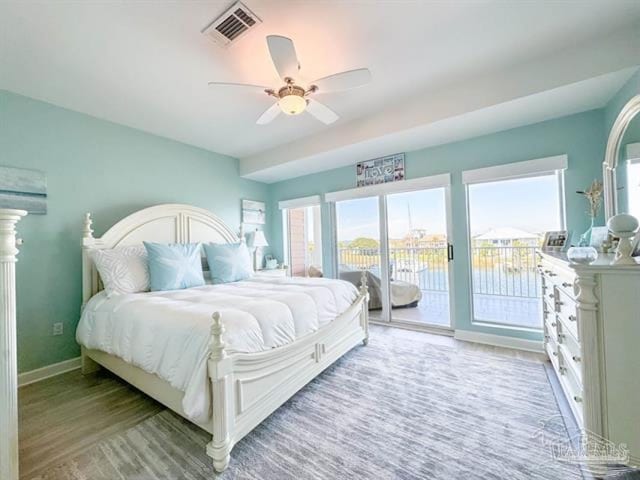 bedroom featuring multiple windows, wood finished floors, visible vents, and access to exterior
