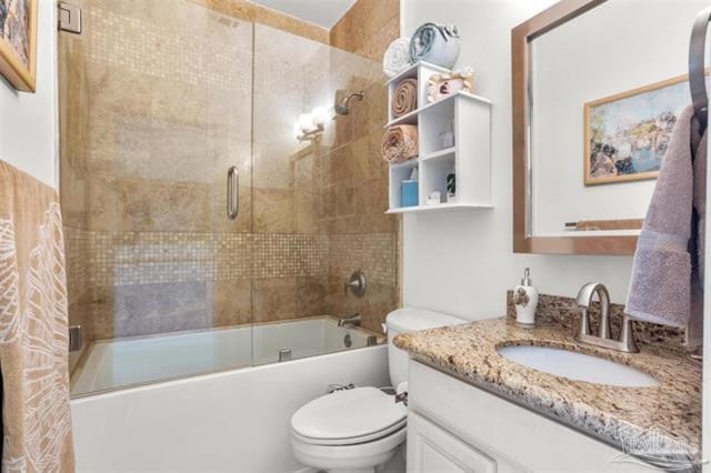 bathroom with toilet, vanity, and shower / bath combination with glass door