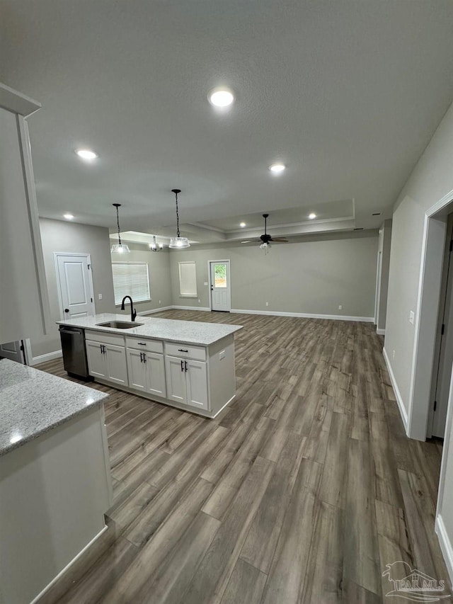 kitchen with ceiling fan, sink, pendant lighting, a center island with sink, and white cabinets