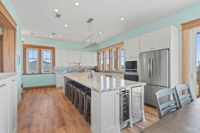 800 Via Deluna Dr, Pensacola Beach, FL 32561 - kitchen with beverage cooler, backsplash, a center island, appliances with stainless steel finishes, and white cabinets
