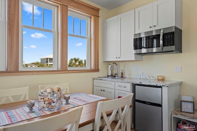 800 Via Deluna Dr, Pensacola Beach, FL 32561 - kitchen with light stone countertops, appliances with stainless steel finishes, white cabinetry, and a sink