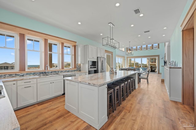 800 Via Deluna Dr, Pensacola Beach, FL 32561 - kitchen with visible vents, light stone counters, stainless steel appliances, white cabinetry, and a sink