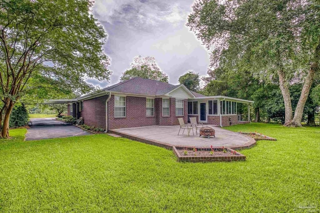 4621 Riley Rd, Milton, FL 32583 - rear view of property featuring an outdoor fire pit, brick siding, a patio area, a sunroom, and a lawn