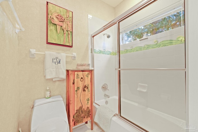 bathroom featuring enclosed tub / shower combo and toilet