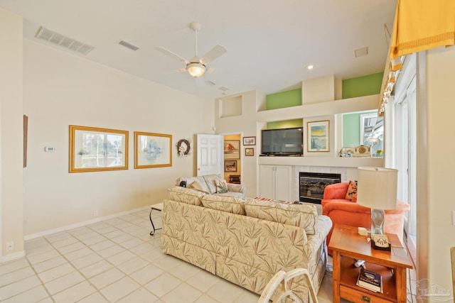 living room with a tile fireplace, ceiling fan, and light tile patterned floors