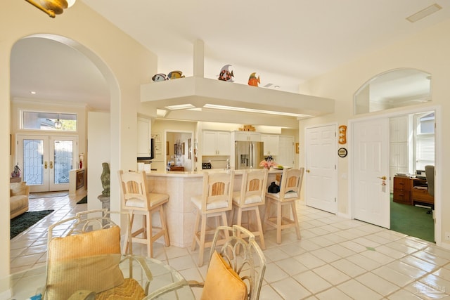 kitchen with french doors, stainless steel refrigerator with ice dispenser, white cabinetry, light tile patterned flooring, and kitchen peninsula