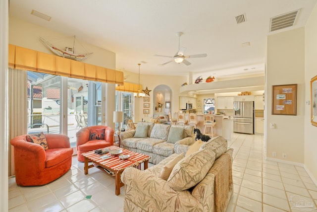 living room featuring light tile patterned flooring and ceiling fan with notable chandelier