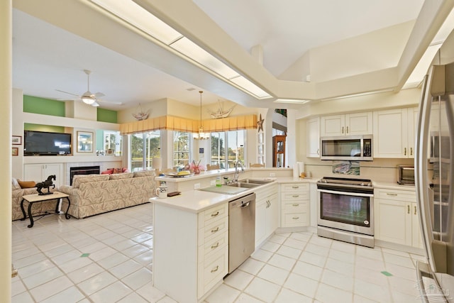 kitchen with ceiling fan with notable chandelier, light tile patterned floors, kitchen peninsula, and appliances with stainless steel finishes