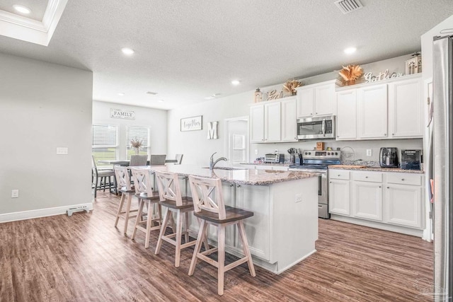 kitchen featuring a kitchen bar, sink, white cabinetry, a center island with sink, and stainless steel appliances