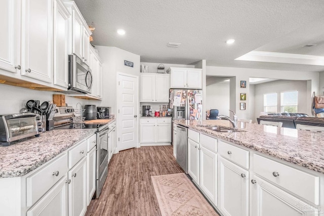 kitchen featuring white cabinetry, sink, light stone counters, light hardwood / wood-style floors, and stainless steel appliances