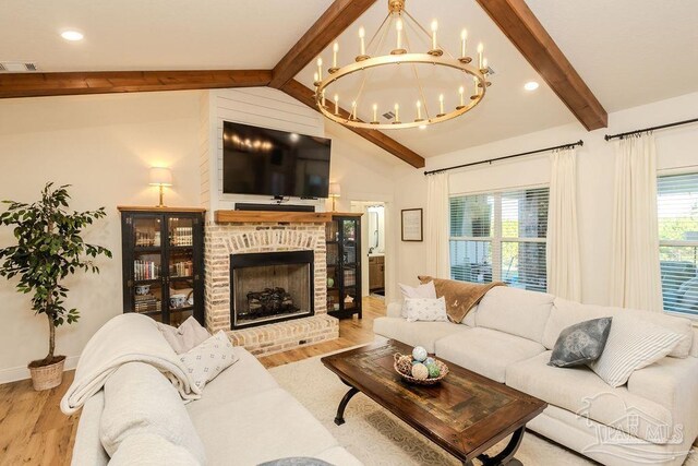 living room featuring vaulted ceiling with beams, a fireplace, visible vents, and wood finished floors