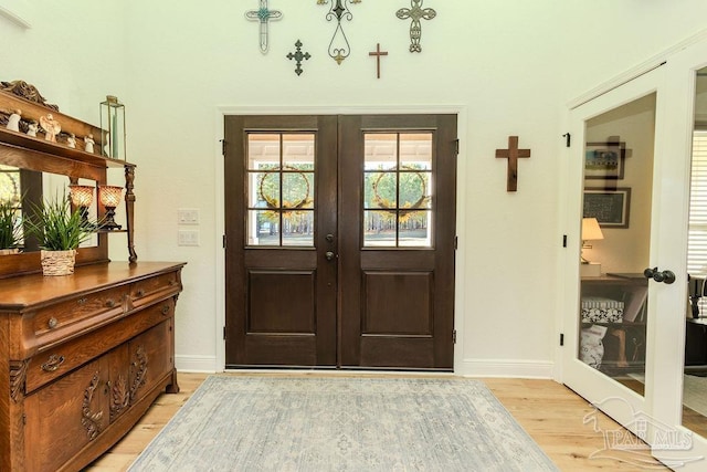 entryway with light wood-type flooring, french doors, and baseboards