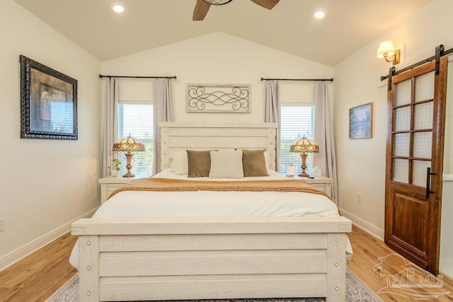 bedroom featuring light wood-type flooring, a barn door, and multiple windows