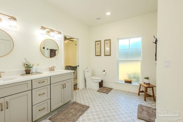 bathroom featuring toilet, a sink, baseboards, and double vanity