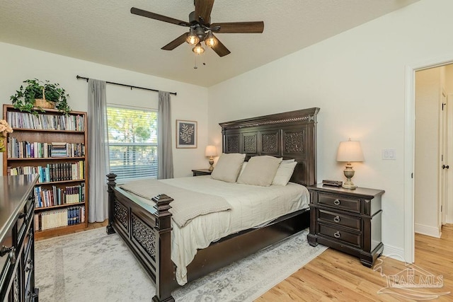 bedroom with a textured ceiling, light wood-type flooring, and a ceiling fan