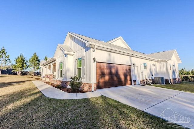 view of side of property featuring a yard, central air condition unit, an attached garage, board and batten siding, and driveway