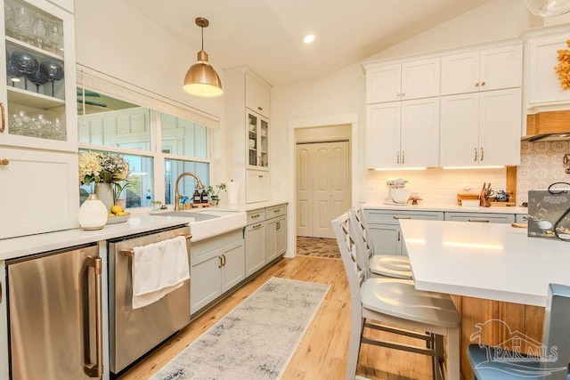 kitchen featuring dishwasher, vaulted ceiling, light countertops, fridge, and a sink