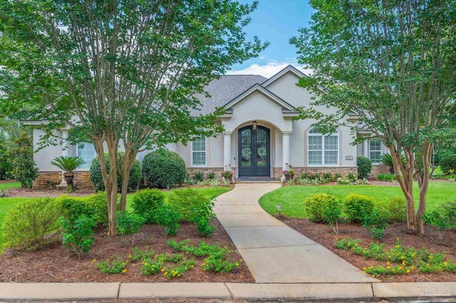 337 Grande Oaks Blvd, Cantonment, FL 32533 - view of front facade with french doors, stone siding, stucco siding, and a front yard