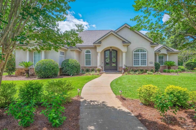 337 Grande Oaks Blvd, Cantonment, FL 32533 - view of front of property with stucco siding, french doors, a front yard, and stone siding