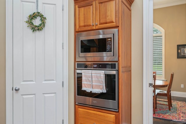 337 Grande Oaks Blvd, Cantonment, FL 32533 - kitchen featuring stainless steel appliances, baseboards, brown cabinetry, and ornamental molding