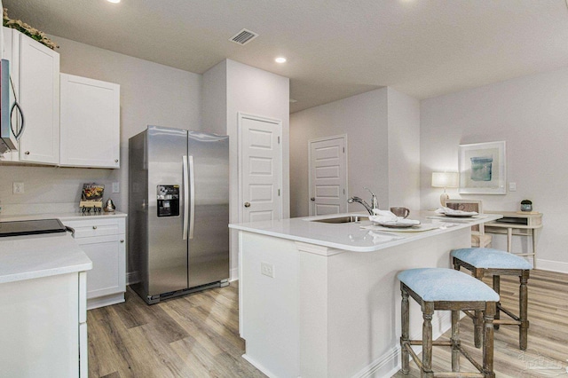 kitchen featuring visible vents, light wood-style flooring, stainless steel appliances, white cabinetry, and a sink