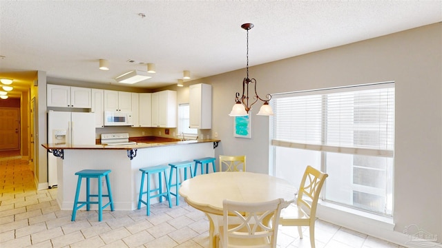 dining space with a textured ceiling, a chandelier, and sink