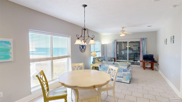 tiled dining space featuring a textured ceiling and ceiling fan with notable chandelier